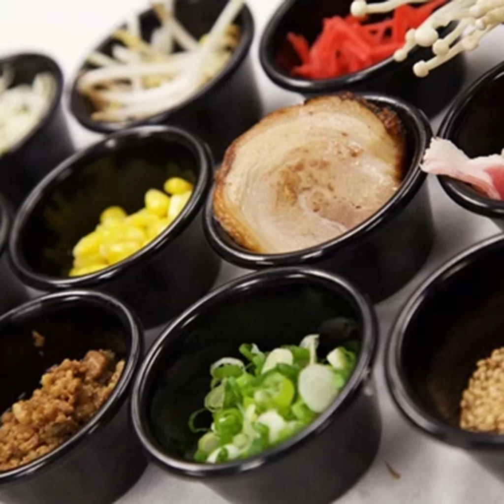 Assorted fresh ramen toppings in small black cups at Ichiddo Ramen, Ramen Restaurant in Poughkeepsie