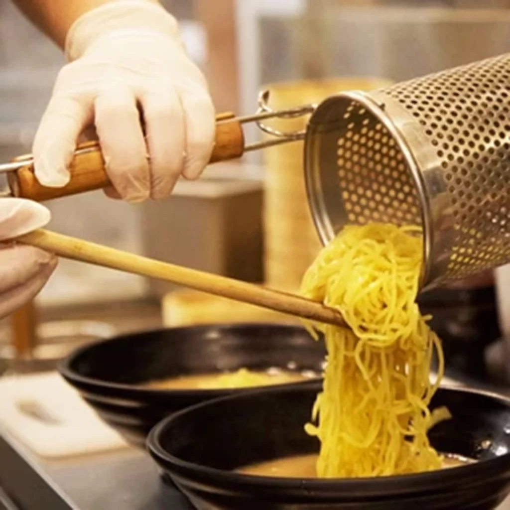 Cook transfers fresh noodles into prepared soup bowl at Ichiddo Ramen, Ramen Restaurant in Poughkeepsie